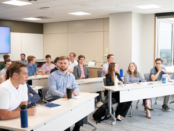 The interns sit at desks talking with one another